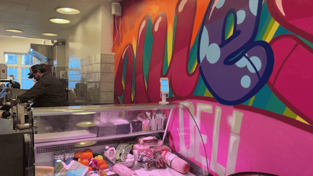 Graffitiwand und Kühltheke mit Käse und Wurst bei Ulle’s Deli in Aabenraa.